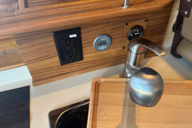 Slide: The Image of 2025 Ranger Tugs R-27 interior with faucet, electrical outlet, and control panel. - 15