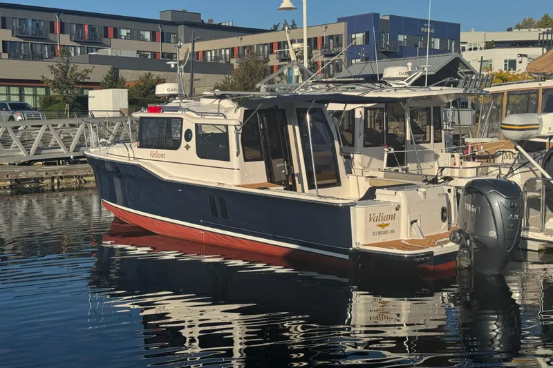 Slide: The Image of 2025 Ranger Tugs R-27 boat docked in marina, reflecting on calm water. - 2