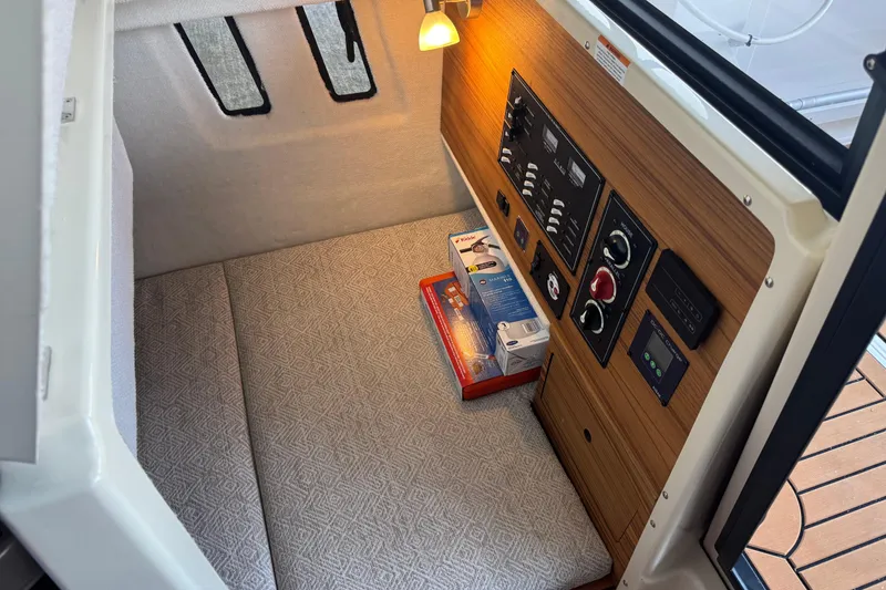 Slide: The Image of 2025 Ranger Tugs R-27 interior cabin with control panel and cozy seating area. - 22