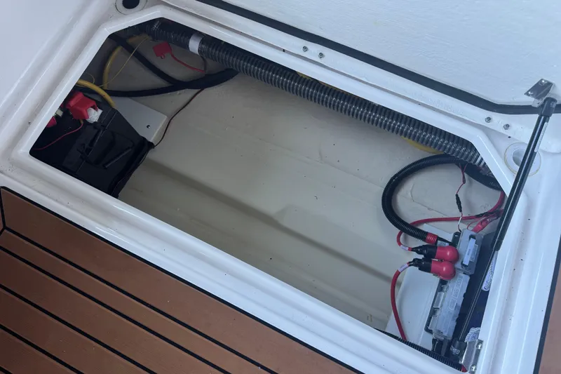 Slide: The Image of 2025 Ranger Tugs R-27 battery compartment with wiring and wooden deck. - 24