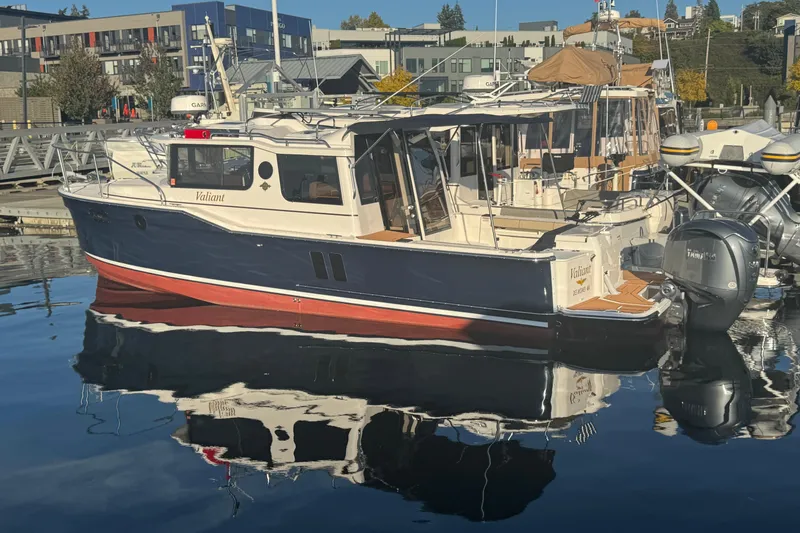 Slide: The Image of 2025 Ranger Tugs R-27 boat docked in a marina, reflecting on calm water. - 3