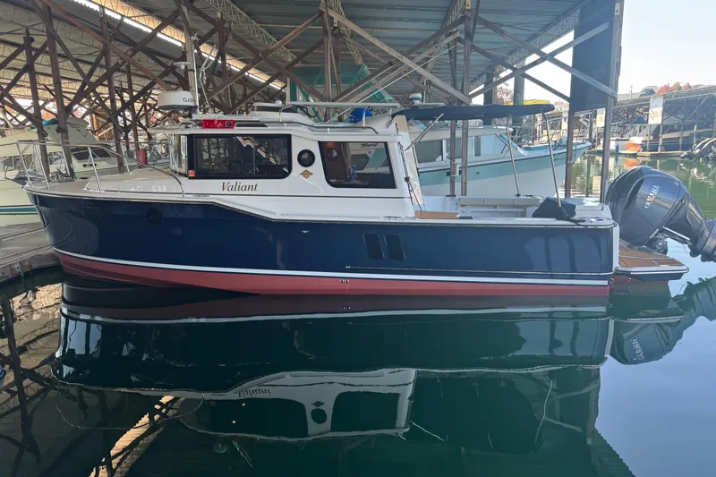 Slide: The Image of 2025 Ranger Tugs R-27 boat docked in a marina, featuring a sleek blue and white design. - 35