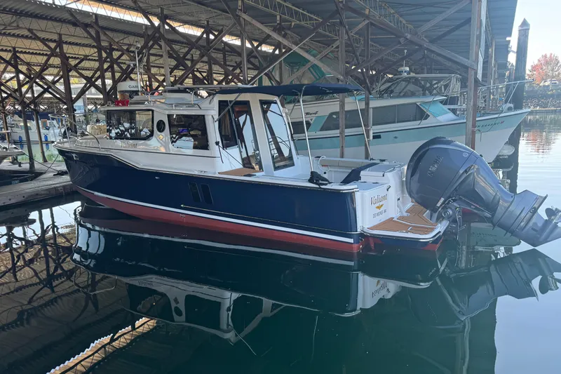 Slide: The Image of 2025 Ranger Tugs R-27 boat docked in a marina, reflecting on calm water. - 5