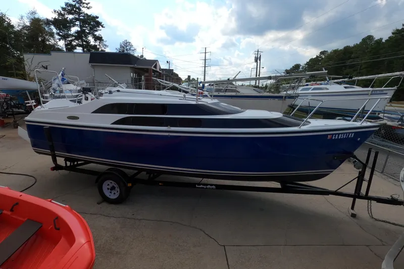 Slide: The Image of 2007 MacGregor 26M sailboat on trailer, blue hull, parked outdoors. - 1
