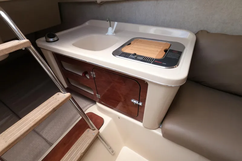 Slide: The Image of Interior of 2007 MacGregor 26M sailboat with compact kitchen area and wooden steps. - 16