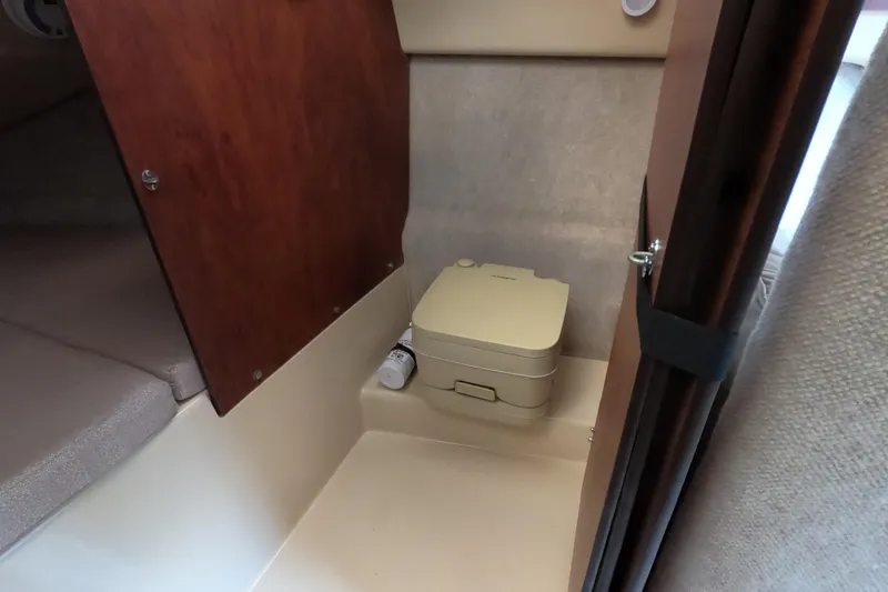 Slide: The Image of 2007 MacGregor 26M interior with compact portable toilet in cabin. - 18