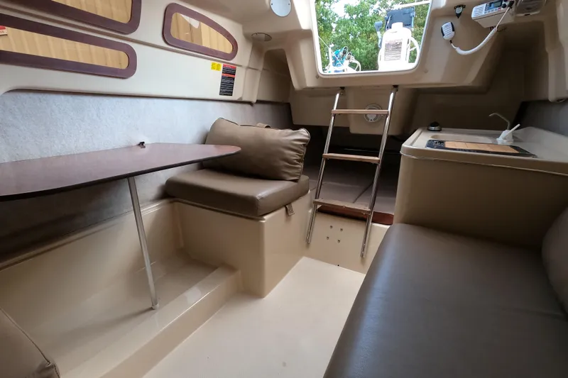 Slide: The Image of Interior of a 2007 MacGregor 26M sailboat, featuring seating, table, and ladder. - 19