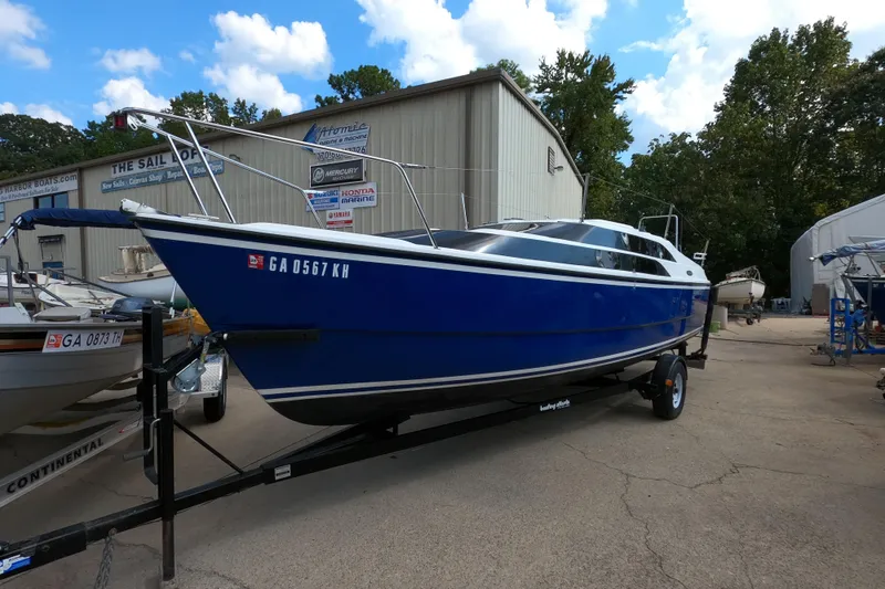 Slide: The Image of Blue 2007 MacGregor 26M sailboat on trailer, parked outside a boat dealership. - 2