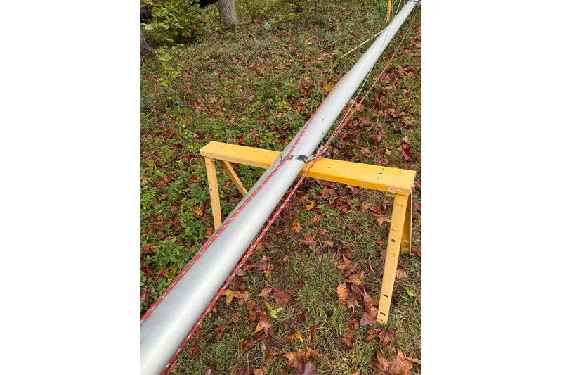 Slide: The Image of Mast of 2007 MacGregor 26M sailboat on yellow sawhorse, surrounded by autumn leaves. - 26