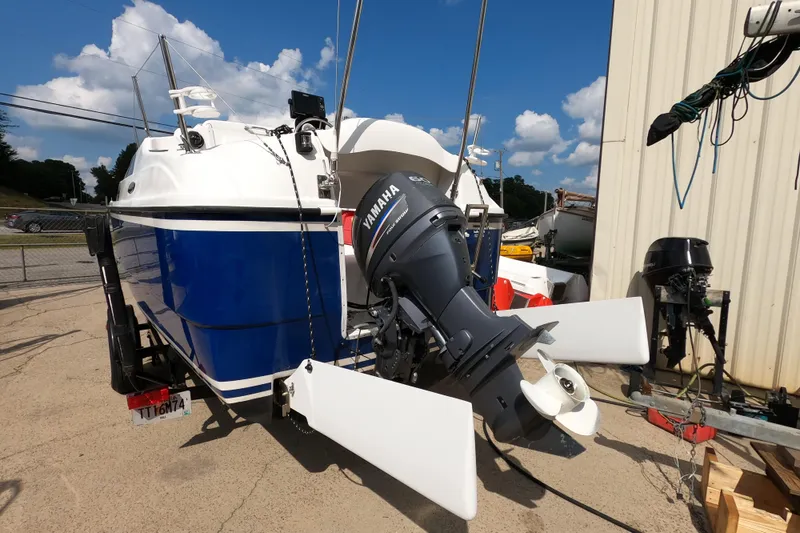 Slide: The Image of 2007 MacGregor 26M sailboat with Yamaha outboard motor, parked outdoors on a sunny day. - 3