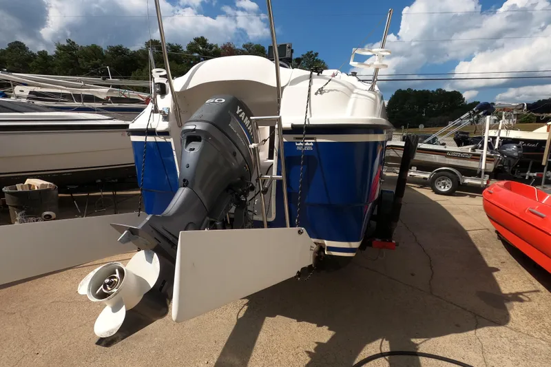Slide: The Image of 2007 MacGregor 26M sailboat with Yamaha outboard motor, parked on a trailer. - 4