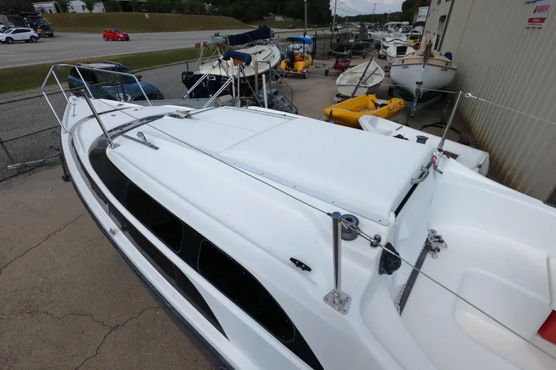 Slide: The Image of 2007 MacGregor 26M sailboat docked, surrounded by other boats and vehicles. - 6