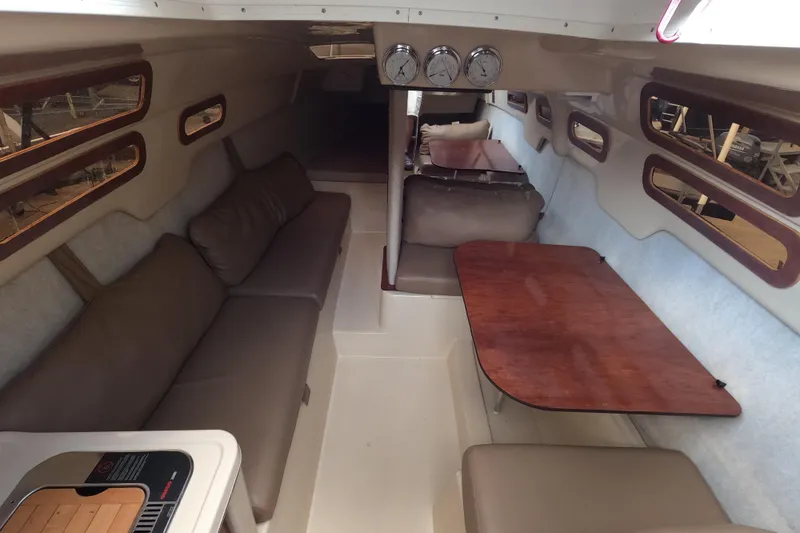 Slide: The Image of Interior of a 2007 MacGregor 26M sailboat with seating and wooden tables. - 9