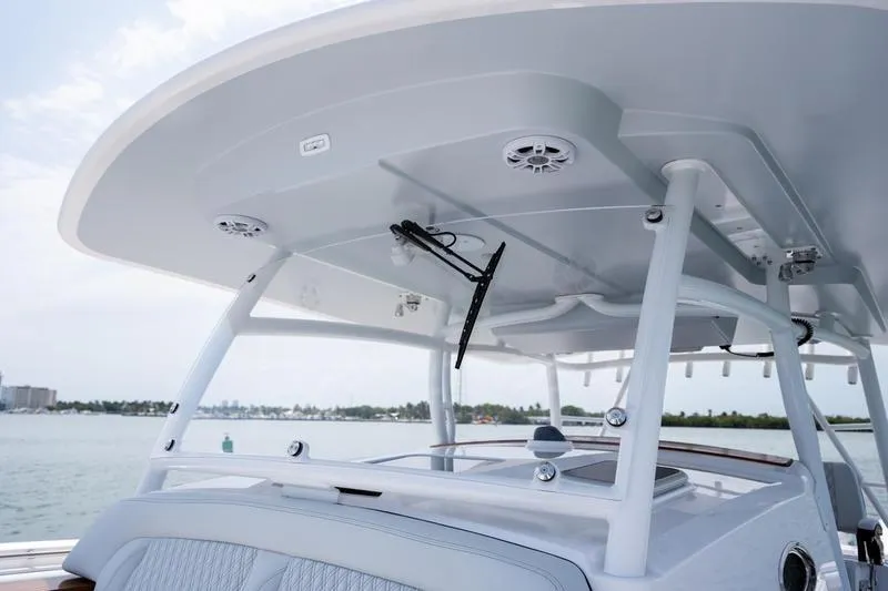 Slide: The Image of 2025 Southport 38 FE boat's helm station with T-top and speakers, on calm water. - 24