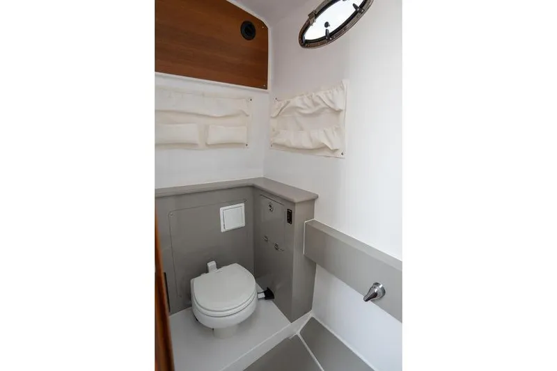 Slide: The Image of 2025 Southport 38 FE boat bathroom interior with toilet and porthole window. - 31
