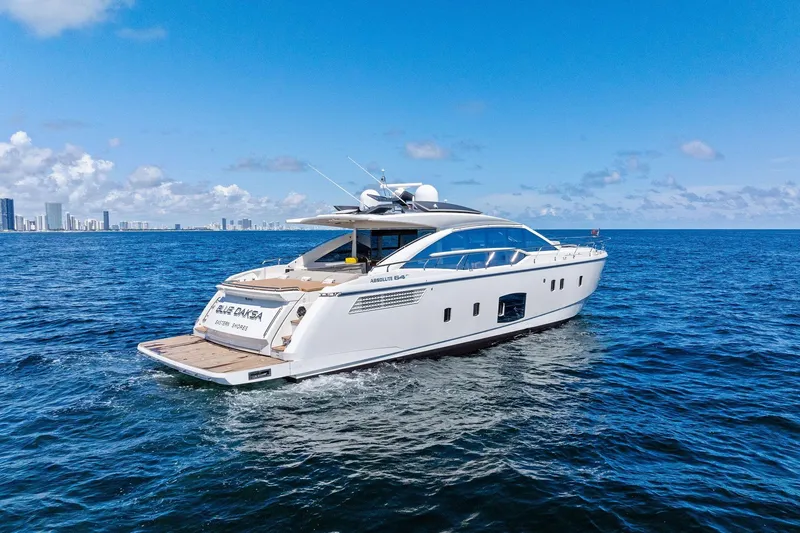 Slide: The Image of Luxury Absolute 64 yacht cruising on open sea, city skyline in background, clear blue sky. - 2