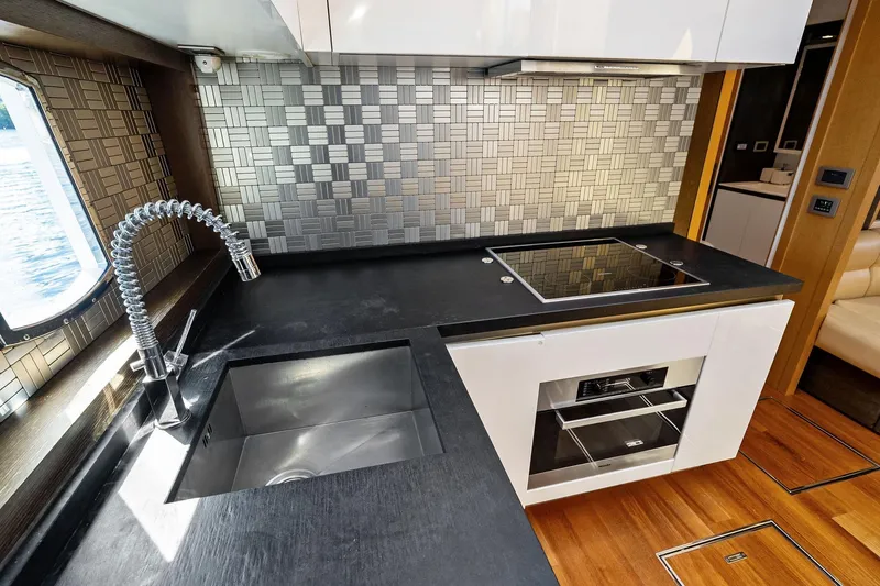 Slide: The Image of Modern yacht kitchen with sleek black countertop, stainless steel sink, and stylish backsplash. - 41