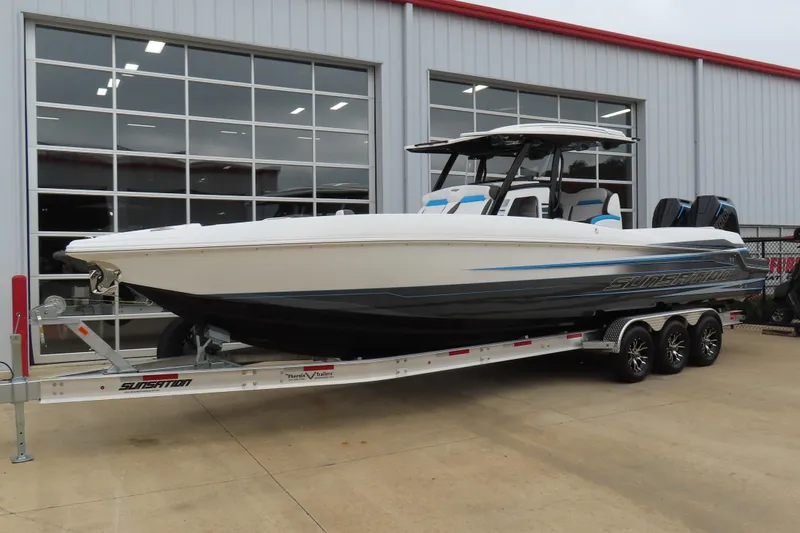 Slide: The Image of 2026 Sunsation 32CCX boat on trailer, parked outside a building with large windows. - 2