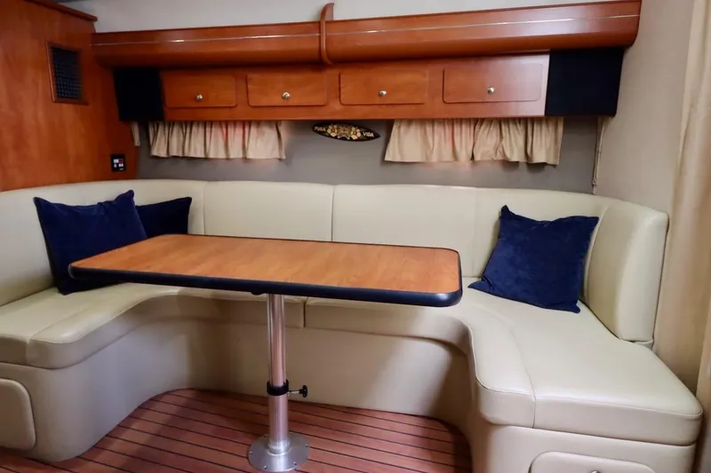 Slide: The Image of 2006 Rinker 360 Express Cruiser interior with beige seating and wooden table. - 19
