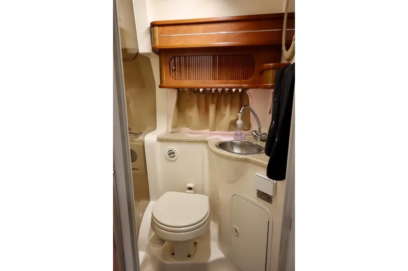 Slide: The Image of 2006 Rinker 360 Express Cruiser bathroom with sink, toilet, and wooden cabinetry. - 25