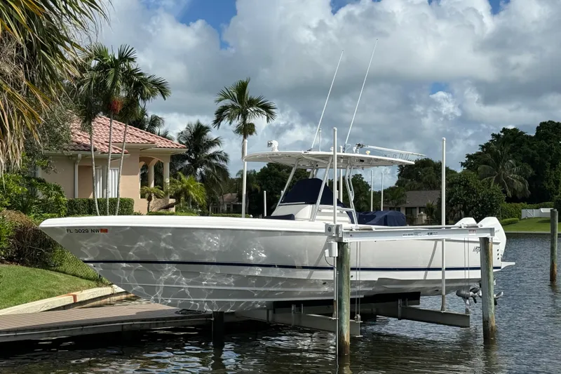 The Image of 2009 Intrepid 323 boat docked by a waterfront home with palm trees. - 0