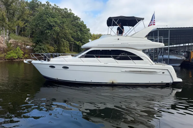 Slide: The Image of 2004 Meridian 341 Sedan yacht on calm water near a wooded shoreline. - 1