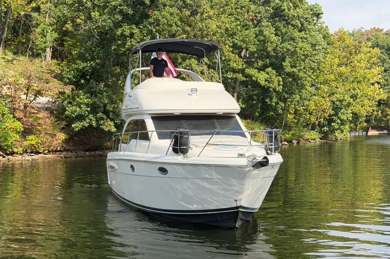 Slide: The Image of 2004 Meridian 341 Sedan yacht cruising on a serene lake with lush green trees. - 11