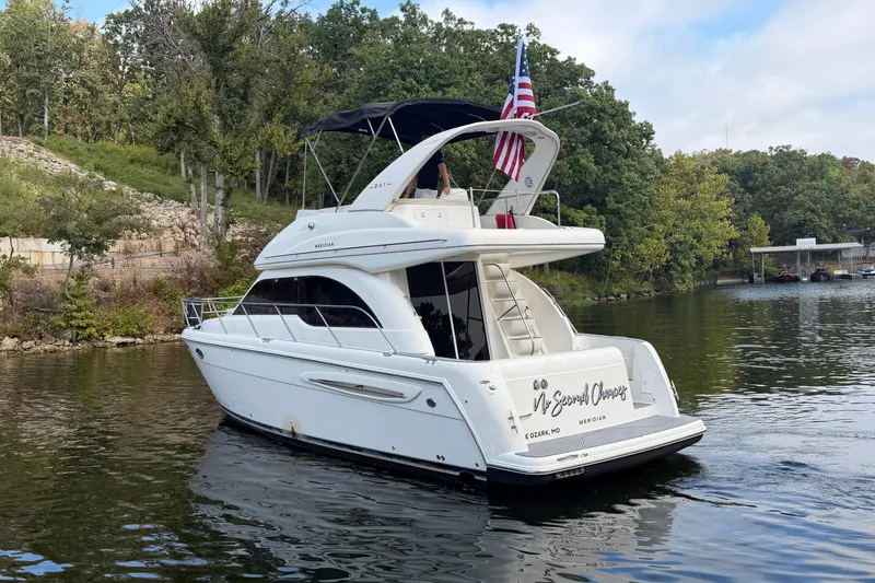 Slide: The Image of 2004 Meridian 341 Sedan yacht cruising on a scenic lake with lush greenery. - 2