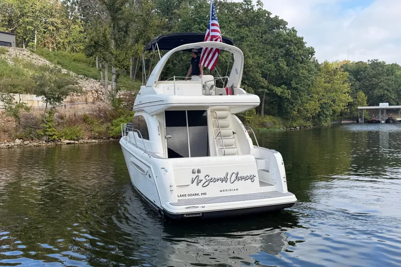 Slide: The Image of 2004 Meridian 341 Sedan yacht on a serene lake with lush greenery. - 3