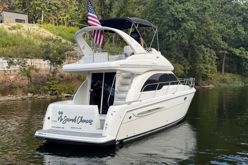 Slide: The Image of 2004 Meridian 341 Sedan yacht on a serene lake with lush greenery. - 4