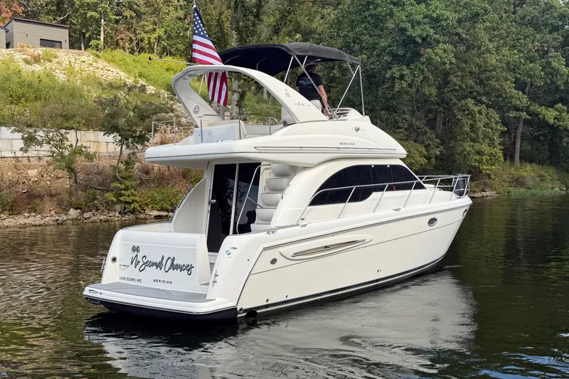 Slide: The Image of 2004 Meridian 341 Sedan yacht on a serene lake with lush greenery. - 5