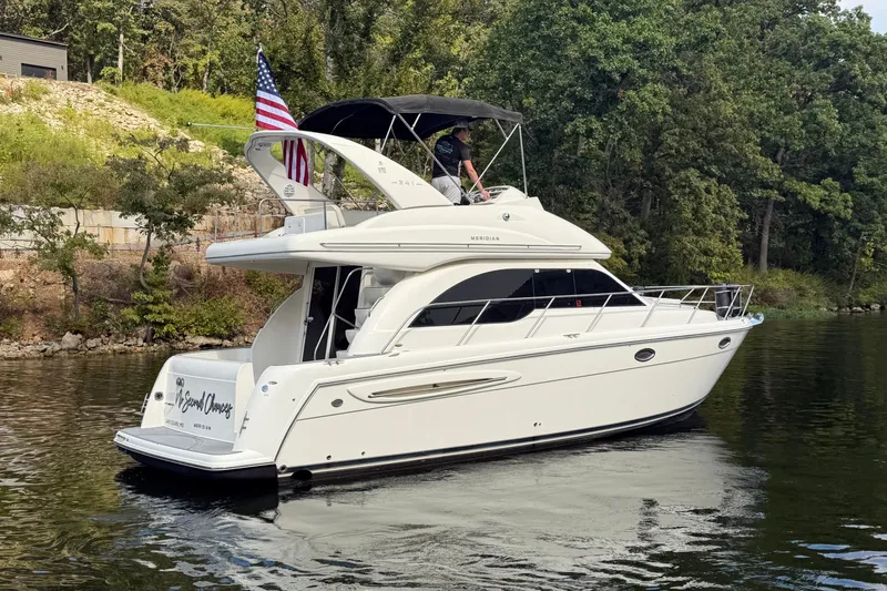Slide: The Image of 2004 Meridian 341 Sedan yacht cruising on a serene lake with lush greenery. - 6