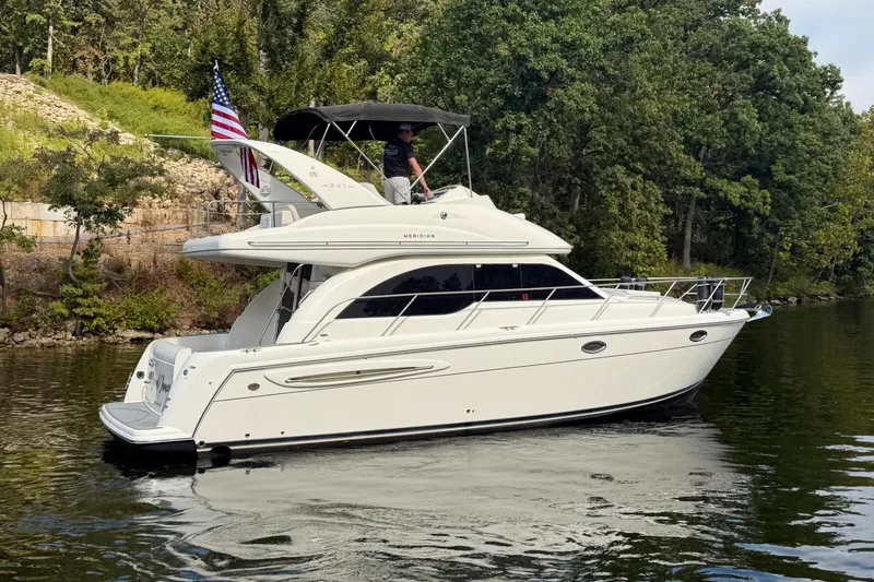 Slide: The Image of 2004 Meridian 341 Sedan yacht cruising on a serene lake, surrounded by lush greenery. - 7