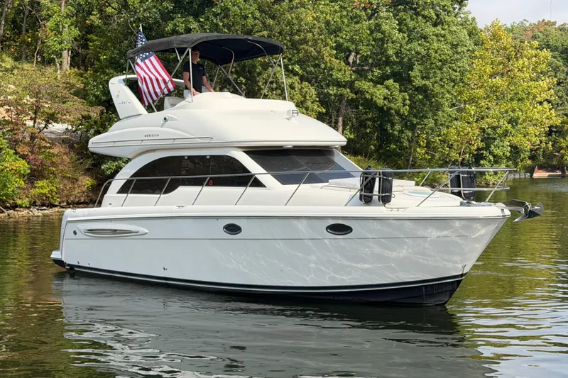 Slide: The Image of 2004 Meridian 341 Sedan yacht on a serene lake with lush green trees. - 9