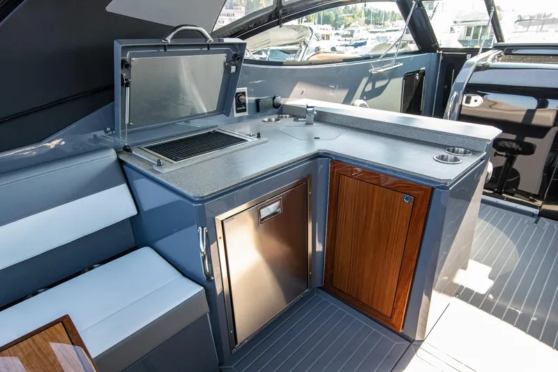 Slide: The Image of 2024 Cruisers Yachts 38 GLS OB interior with kitchenette, grill, and seating area. - 4