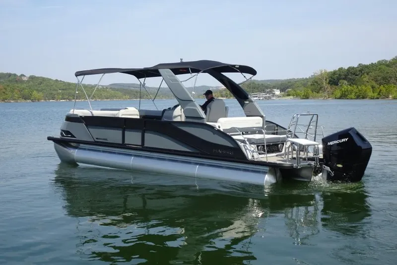 Slide: The Image of 2026 Harris Grand Mariner 250 pontoon boat on a serene lake with lush green shoreline. - 3