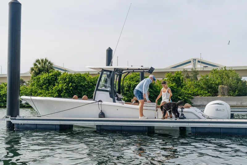 Slide: The Image of 2026 Sea Hunt Ultra 265 SE boat docked with people and a dog onboard. - 13