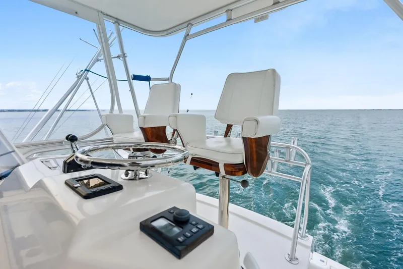 Slide: The Image of 2006 Bertram 39 Convertible yacht helm with ocean view, featuring white captain's chairs and steering wheel. - 35