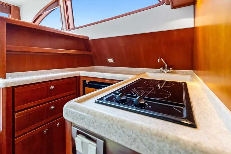 Slide: The Image of 2006 Bertram 39 Convertible yacht kitchen with stove, sink, and wooden cabinetry. - 46
