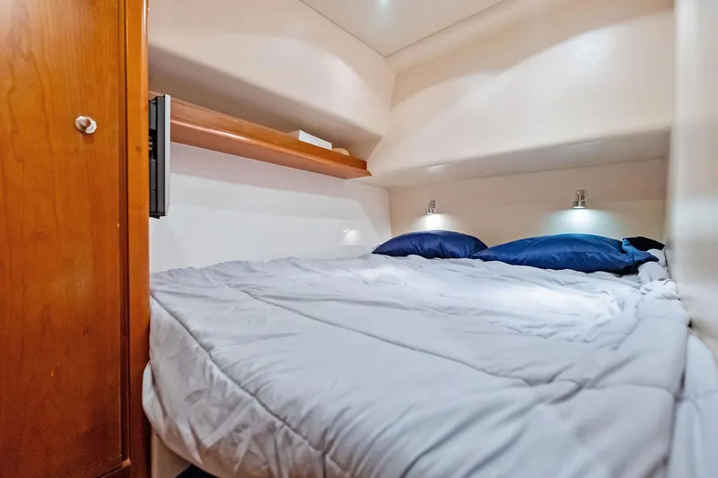 Slide: The Image of Cozy cabin bedroom in 2006 Bertram 39 Convertible yacht with wooden accents and soft lighting. - 50