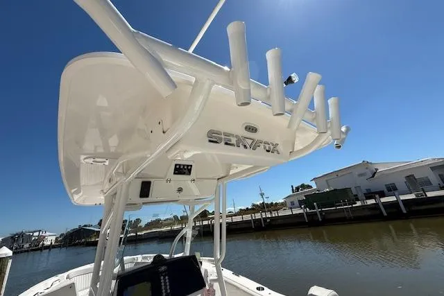 Slide: The Image of 2023 Sea Fox 268 Commander boat with rod holders, docked by a sunny waterfront. - 20