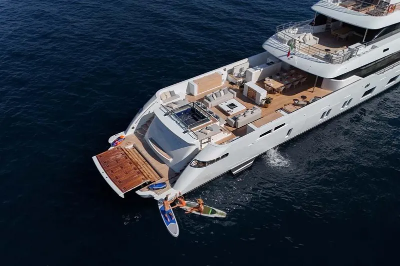 Slide: The Image of 2023 Canados Expedition Yacht on open sea with paddleboarders nearby. - 44