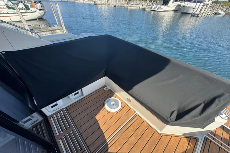 Slide: The Image of 2017 Sea Ray Sundancer 400 boat deck with black cover, docked at marina. - 10