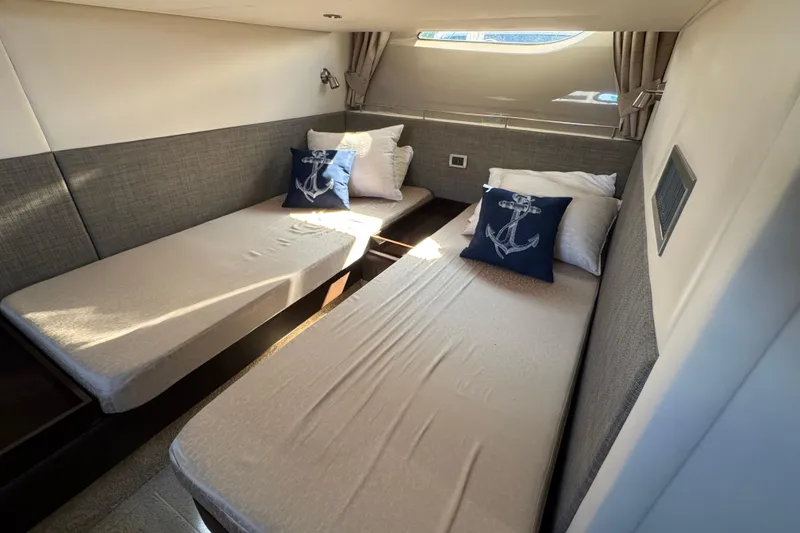Slide: The Image of 2017 Sea Ray Sundancer 400 cabin with twin beds and nautical-themed pillows. - 32