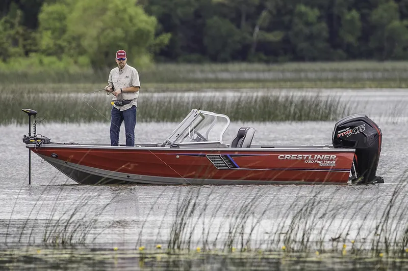 Slide: The Image of 2018 Crestliner 1750 Fish Hawk SC boat on trailer, parked outdoors under blue sky. - 0