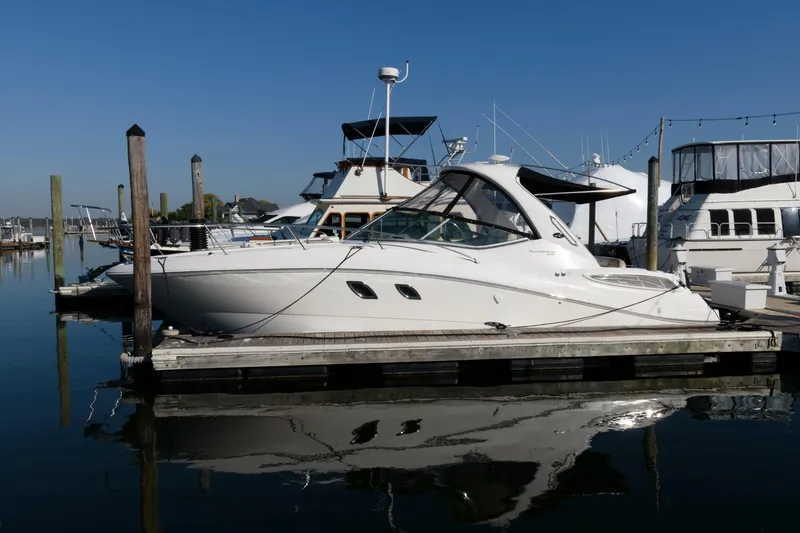 Slide: The Image of 2012 Sea Ray 330 Sundancer docked at marina, reflecting on calm water. - 3