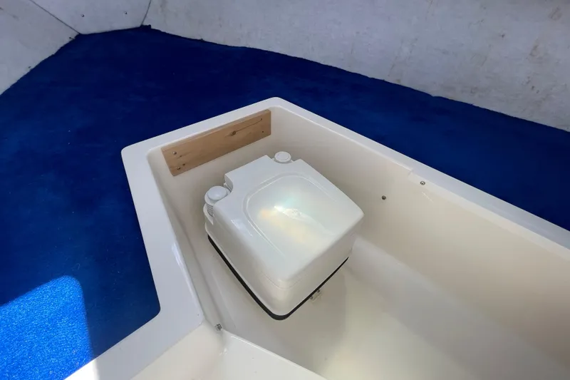 Slide: The Image of 1997 Wellcraft 240 Coastal cabin interior with blue bedding and portable toilet. - 21