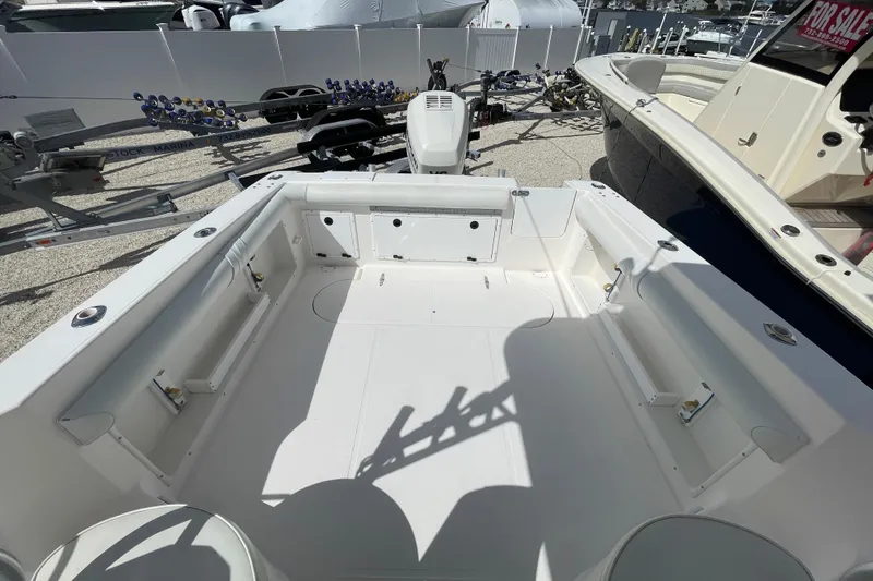 Slide: The Image of 1997 Wellcraft 240 Coastal boat interior, spacious deck, white seating, outdoor marina setting. - 5