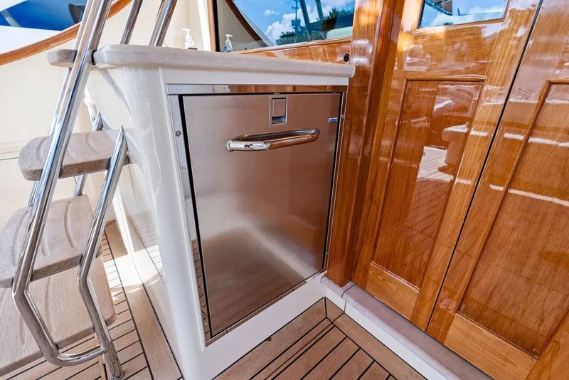 Slide: The Image of 2018 Palm Beach Motor Yachts PB55 Flybridge, stainless steel appliance, wooden cabinetry, and stairs. - 13