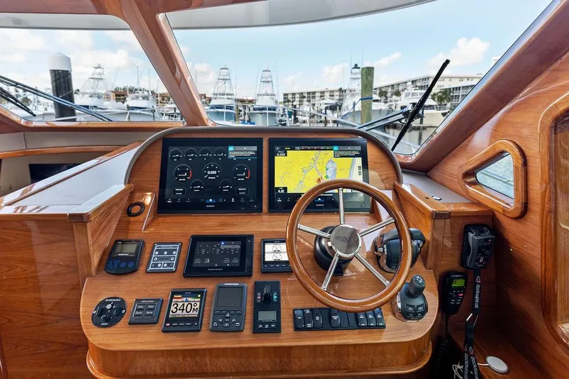 Slide: The Image of 2018 Palm Beach Motor Yachts PB55 Flybridge helm with navigation screens and wooden steering wheel. - 39
